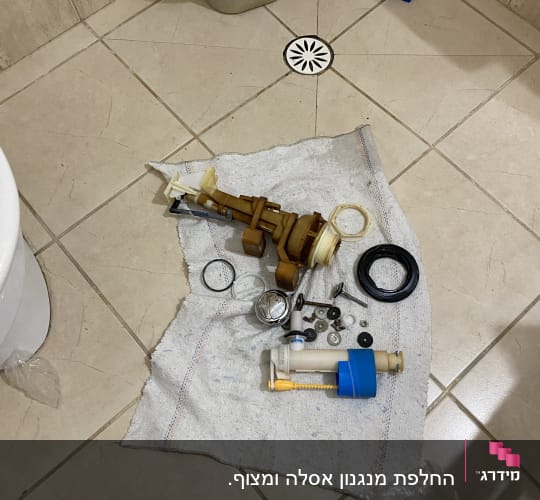 חלקי אינסטלציה על מגבת ברצפת חדר אמבטיה